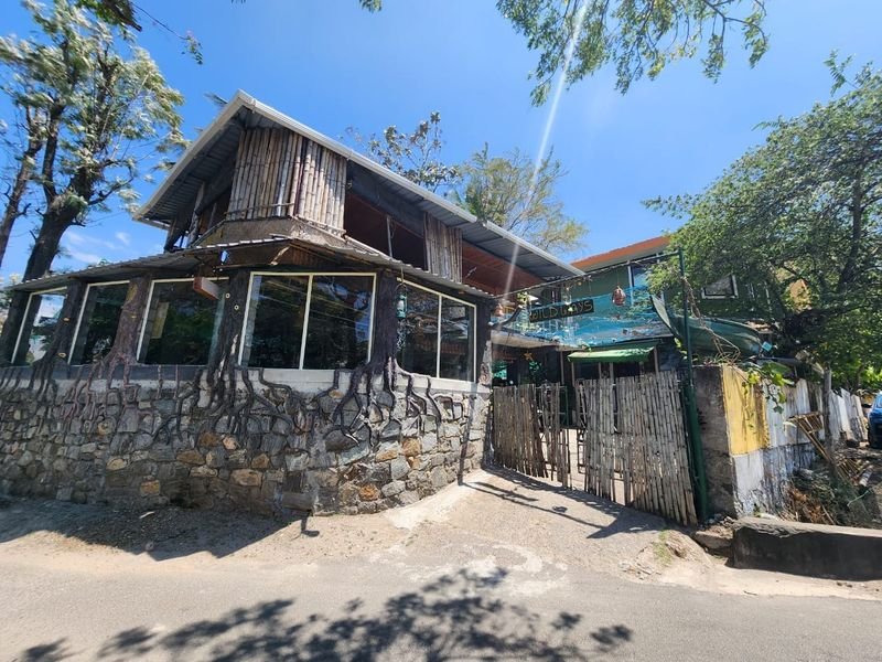 Homestay exterior with stone walls and a wooden upper floor