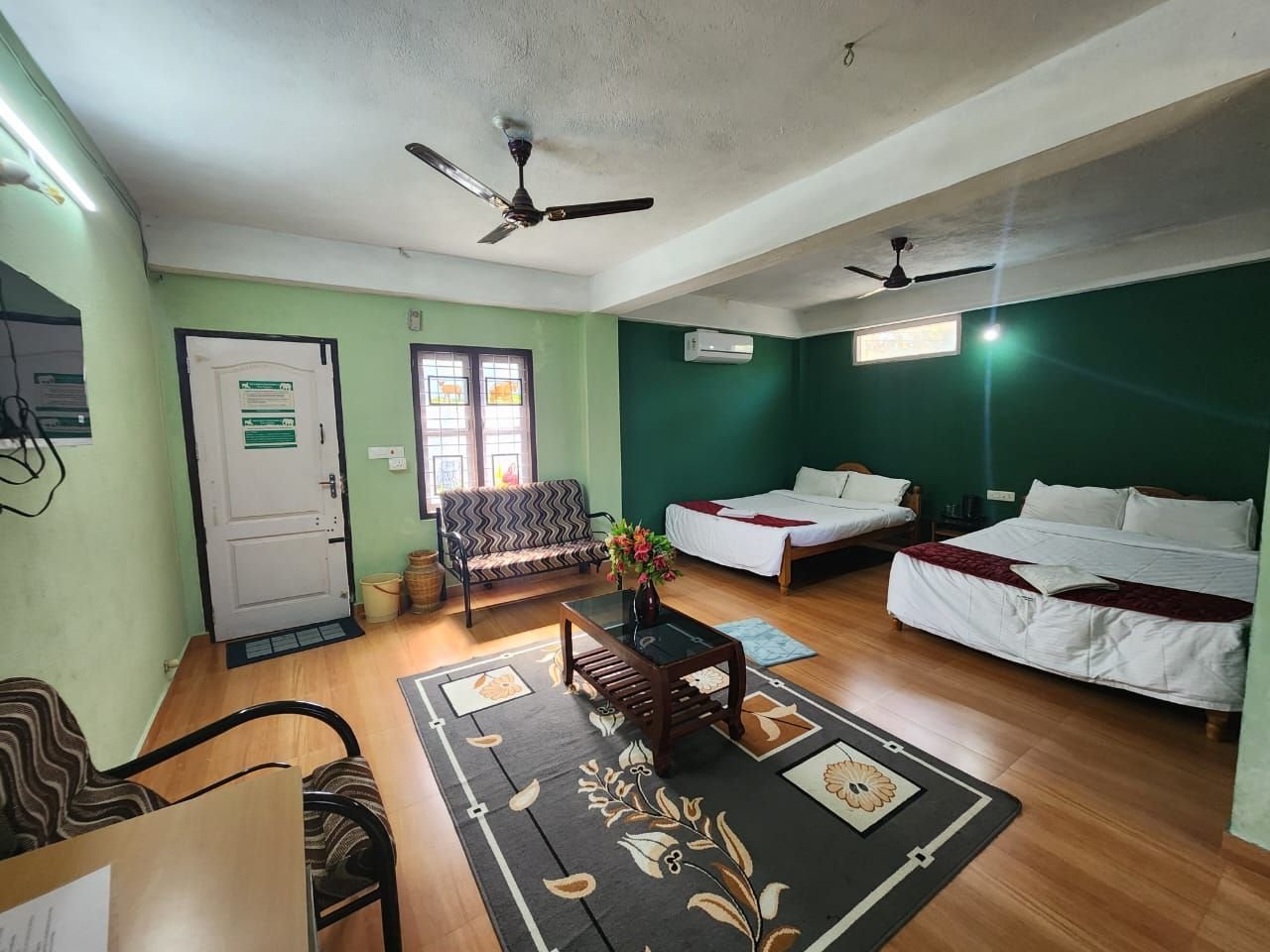Spacious family room with two large beds, sofa and green walls